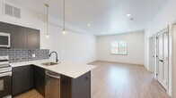 Located on Germantown Avenue in Philadelphia's 19144 neighborhood, this well-appointed one-bedroom, one-bathroom unit offers a thoughtfully designed single-floor layout with modern finishes throughout. The open-concept kitchen and living area serves as the heart of the space, featuring dark cabinetry with a gray subway tile backsplash, a full suite of stainless steel appliances — including a refrigerator, range, microwave, and dishwasher — and a peninsula with a white quartz countertop and undermount sink. Warm-toned wood-look flooring runs throughout the main living areas, complementing the crisp white walls and recessed lighting. Gold-accented pendant lights above the peninsula add a contemporary touch, while a window in the living area brings in natural light and outdoor views. The bedroom is a comfortable, well-proportioned room with its own window overlooking the surroundings, recessed lighting, and two closets with clean white panel doors and matte black hardware. The bathroom is finished with light tile flooring, a warm wood vanity with gold hardware, and a full tub-shower combination featuring striking vertical navy blue tile. Additional utility and closet space rounds out the practical layout of this move-in ready unit.