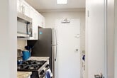 Located at 2000 N Adams St in Arlington, VA, this one-bedroom, one-bathroom unit offers a well-designed layout across a single floor. The open-concept living and dining area is bright and inviting, featuring light wood-style flooring, neutral warm-toned walls, and multiple windows fitted with blinds that allow generous natural light to filter through. A glass door leads directly to a private patio, extending the living space outdoors.

The kitchen is efficiently designed and well-appointed, showcasing white shaker-style cabinetry with brushed nickel hardware, granite countertops, a stainless steel sink, and stainless steel appliances including a gas range, microwave, refrigerator, and dishwasher. A pantry provides additional storage convenience.

The generously sized bedroom features plush carpeting, a ceiling fan with light fixture, a window with outdoor views, and the added benefit of two closets offering ample storage. Three closets total are distributed throughout the unit.

The bathroom includes a full tub-shower combination with clean white tile surround and brushed nickel fixtures. The overall aesthetic throughout the unit is clean and contemporary, with a neutral palette and modern finishes that create a cohesive, move-in-ready living environment.