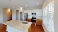 Located at 329 Broomsedge Trail in Chattanooga, Tennessee, this single-story home offers a well-designed, open-concept floor plan with a clean, modern aesthetic. Rich hardwood-style flooring runs throughout the main living areas, complemented by neutral gray walls and crisp white trim that create a bright, welcoming atmosphere.

The kitchen is a standout feature, boasting a large granite-topped island with an integrated sink, stainless steel appliances including a refrigerator, electric range, and microwave, and a two-tone cabinet design pairing white upper cabinets with warm wood lower cabinets. Pendant lighting above the island adds a refined touch. The kitchen opens seamlessly into a spacious living area filled with natural light from multiple windows and fitted with a ceiling fan.

The bedrooms are carpeted for comfort, each equipped with ceiling fans and generous closet space, including walk-in closets. The bathrooms feature granite vanity tops, white cabinetry, large mirrors, and hardwood-style flooring. One bathroom includes accessibility grab bars and a walk-in shower, while another offers a full tub-shower combination. A dedicated laundry room accommodates a full-size washer and dryer with additional shelving overhead. The home's thoughtful layout and quality finishes make it a functional and comfortable living space.