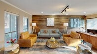 Located at 10010 Kempwood Dr in Houston, TX, this single-floor commercial space blends rustic charm with modern functionality. The interior is thoughtfully designed to accommodate both professional work and client interaction.

The reception and front office area features dark hardwood-style flooring, warm taupe walls, and large windows fitted with blinds that invite an abundance of natural light. A substantial natural wood desk serves as the central workstation, accompanied by mid-century modern wooden chairs. Track lighting overhead provides supplemental illumination, and a glass-paneled entry door connects the space directly to the exterior.

Adjacent to the front office, an open lounge area makes a striking impression with a full accent wall clad in reclaimed horizontal wood planks. The seating arrangement includes a tufted gray sofa flanked by two caramel leather armchairs, all centered around a sculptural gold coffee table atop a layered area rug. Tripod floor lamps add a warm, designer touch to the space.

A dedicated private office is also present, continuing the reclaimed wood wall aesthetic and featuring a large executive desk, ergonomic seating, and a display board. Crown molding runs throughout, tying the interiors together with a refined finish. The overall ambiance is professional yet inviting, making this space well-suited for client-facing business operations.