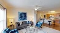 This single-floor residence offers a thoughtfully designed layout that balances comfort and functionality throughout. The spacious living room serves as the heart of the home, featuring plush carpet flooring, a ceiling fan with light fixture, large windows that invite natural light, and generous wall space highlighted by bold statement artwork. The open flow connects seamlessly to a breakfast bar area, making it ideal for both relaxing and entertaining.

The kitchen is well-equipped with warm honey-toned cabinetry, light countertops, and a full suite of white appliances including an electric range, built-in microwave, refrigerator, and dishwasher. Wood-look flooring runs throughout the kitchen, adding warmth and easy maintenance.

The bedroom is a tranquil retreat finished with soft carpet, a ceiling fan, and a window dressed with drapes that allow for light control and privacy. The room offers a calm, restful ambiance with neutral wall tones throughout.

Two full bathrooms each feature a tub-shower combination with curtain, tile flooring, and clean, bright finishes. A dedicated in-unit laundry room provides added convenience, housing a side-by-side washer and dryer along with overhead shelving for storage. Overall, this residence delivers a comfortable and practical living environment.