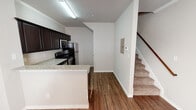 This two-story residence located on SE 16th Street in Mineral Wells, Texas, offers a well-organized layout spread across two distinct levels. The main floor centers around an open-concept living and kitchen area, where wood-look flooring runs throughout, creating a cohesive and easy-to-maintain surface. The kitchen is a functional highlight, equipped with a full suite of stainless steel appliances including a refrigerator, electric range, built-in microwave, and dishwasher. Dark espresso-toned cabinetry extends to the upper walls, providing ample storage, while granite-style countertops and a peninsula with a stainless steel sink add practical workspace. Crown molding accents the dining area adjacent to the kitchen, lending a polished finish. A carpeted staircase leads to the upper level, where the bedrooms are situated. Each bedroom features plush carpet flooring, neutral-toned walls, a ceiling fan with light fixture, and a window that allows natural light to fill the space. The bathroom includes a granite-topped vanity with dark cabinetry, a tub-shower combination, a wall-mounted storage cabinet, and wood-look flooring. Overall, the space maintains a clean, neutral palette throughout.