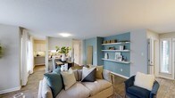 Located at 7303 Hihenge Ct in Raleigh, NC, this single-floor residence offers a thoughtfully designed open-concept layout that connects the living, dining, and kitchen areas in one cohesive space. The living area serves as the heart of the home, anchored by a striking teal accent wall adorned with floating shelves — an ideal display for décor and personal touches. Durable hardwood-style flooring runs throughout, adding warmth and continuity to the space. The kitchen is visible from the main living area and features white cabinetry, providing a clean and bright aesthetic. A dedicated dining area sits between the kitchen and living room, creating a natural flow perfect for everyday living and entertaining. The textured ceiling and neutral wall tones complement the bolder accent elements, striking a balance between understated and expressive. The overall ambiance is modern and inviting, with a practical single-level layout that makes the space easy to navigate. This Raleigh home combines functional design with contemporary style, making it a comfortable and visually appealing place to call home.