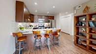 Located on Salt Lake City's historic East South Temple corridor, this 2-bedroom, 2-bathroom residence offers a thoughtfully designed single-floor layout. The open-concept living, dining, and kitchen area forms the heart of the home, bathed in natural light from large sliding glass doors that lead to an outdoor patio with views of surrounding greenery. The kitchen is a standout feature, showcasing rich dark-wood cabinetry, white quartz countertops, a classic subway tile backsplash, stainless steel appliances, and a generous island with bar seating — ideal for both cooking and entertaining. Light wood-style flooring flows throughout the main living areas, lending warmth and continuity. The primary bedroom offers a comfortable, carpeted retreat with sliding door access to natural light and ample closet space. The second bedroom is equally well-sized, featuring a built-in closet and bright, neutral finishes. Both bathrooms are finished with dark wood vanities, quartz counters, and marble-style tile surrounds — one featuring a glass-enclosed walk-in shower, the other a full soaking tub. A utility room and multiple closets provide excellent storage throughout this efficiently designed and elegantly finished residence.