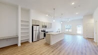Located at 283 Capitol Avenue in Winder, Georgia, this two-story, 3-bedroom, 3-bathroom home offers a thoughtfully designed layout spread across two well-proportioned floors. The main level features an open-concept kitchen, dining, and living area bathed in natural light from large windows. The kitchen is appointed with sage-toned cabinetry, stainless steel appliances including a refrigerator, microwave, and range, and a large center island with a granite countertop and undermount sink. Pendant lighting and track lighting illuminate the space, while light-toned luxury vinyl plank flooring flows throughout the main level. A ceiling fan anchors the living area, which includes a door providing outdoor access. A carpeted staircase leads to the upper floor, where three bedrooms offer plush carpet flooring, ceiling fans, and natural light through windows with exterior views. The primary bedroom includes a spacious walk-in closet with wire shelving. Three full bathrooms are distributed across both floors, each featuring granite-topped vanities and LVP flooring; one includes a walk-in shower with built-in shelving. A dedicated laundry room with wire shelving and hookups adds everyday convenience to this clean, modern home.