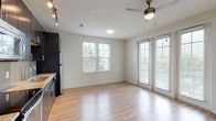 Located at 17000 La Cantera Pkwy in San Antonio, TX, this single-floor unit offers a clean, contemporary design throughout. The open-concept living and kitchen area is anchored by light wood-style flooring, a ceiling fan with light fixture, and track lighting that illuminates the space effectively. Large windows and a glass door allow generous natural light to flow in while providing outdoor views, creating a bright and airy atmosphere.

The kitchen is outfitted with dark espresso cabinetry, granite-style countertops, a mosaic tile backsplash, and a full suite of stainless steel appliances, including a refrigerator, electric range with built-in microwave, and dishwasher. A double basin sink with a brushed nickel faucet completes the functional workspace.

The bedroom features plush neutral carpeting and multiple windows that continue the theme of natural light throughout the unit. A programmable thermostat is conveniently mounted in the hallway, which also features a ceiling vent for climate control.

The bathroom includes tile flooring, a soaking tub with tiled surround, a dark vanity with granite-style countertop, an undermount sink, and a framed mirror, offering a well-appointed and practical finish.