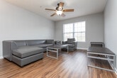 Located at Campus Pointe Circle in Gainesville, GA, this single-floor unit offers a practical and well-organized layout designed for comfortable everyday living. The kitchen is outfitted with warm honey-toned wood cabinetry lining both sides of the galley-style space, complemented by white appliances including a refrigerator, electric range with microwave above, and dishwasher. Rich hardwood-style flooring runs throughout the main living areas, adding warmth and continuity. Adjacent to the kitchen, the dining area features a pass-through counter bar and is highlighted by an elegant chandelier overhead, creating a welcoming space for meals and gatherings. The living room offers a relaxed atmosphere with a ceiling fan and neutral walls, providing a versatile space for everyday use. Two bedrooms are carpeted for comfort, each featuring ceiling fans with light fixtures and natural light from windows. Both rooms include closet storage and offer a quiet, restful environment. The unit includes two bathrooms, each appointed with wood-toned vanity cabinetry, a large mirror, and light fixtures above. The consistent use of neutral gray tones on the walls throughout the unit, paired with the warm flooring, creates a cohesive and inviting atmosphere from room to room.