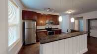Located at 100 S Skyloft Dr in Asheville, NC, this single-floor unit offers a thoughtfully designed layout with a cohesive aesthetic throughout. Rich, polished concrete floors extend across every room, providing a sleek, low-maintenance foundation that ties the space together.

The kitchen is a standout feature, showcasing warm cherry wood cabinetry, dark granite countertops, and a full suite of stainless steel appliances including a refrigerator, electric range, and microwave. A central island with a built-in sink and pendant lighting above creates both a functional workspace and a natural gathering point. The kitchen opens directly to the living area, which features a ceiling fan and a distinctive wood-panel accent wall that adds texture and warmth.

The bedrooms are generously sized, each equipped with ceiling fans and natural light from windows with blinds. Closets with wire shelving provide organized storage. The primary bathroom features a fully tiled walk-in shower with mosaic floor tile detailing and a window for natural light. A second bathroom offers a rich wood vanity with granite countertop and a framed mirror with bar lighting above.

A wide hallway entry connects all areas of the unit, creating a smooth, open flow from room to room throughout this well-appointed Asheville home.
