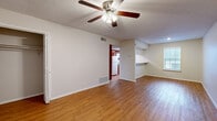 This single-floor, 2-bedroom, 1-bathroom unit offers a functional and comfortable layout across a compact yet efficient floor plan. The open living room serves as the heart of the space, featuring warm wood-look flooring, a textured ceiling, and a ceiling fan with integrated lighting. A pass-through countertop connects the living area to the kitchen, which is equipped with warm-toned wooden cabinetry, white appliances including a refrigerator, range, and over-the-range microwave, along with ample counter space. Natural light enters through windows, adding brightness to the living area.

The primary bedroom is a well-sized room featuring carpet flooring, a ceiling fan, and two windows that allow for generous natural light. It includes a spacious walk-in closet with built-in shelving and hanging rods. The secondary bedroom also features carpet flooring, neutral walls, and a standard closet, making it suitable as a guest room or home office. Both rooms offer a calm, neutral ambiance.

The bathroom is clean and straightforward, featuring a tiled tub-shower combination, wood-look flooring, a toilet, and overhead cabinetry for storage. A hallway connects the main living spaces to the bedrooms and bathroom, contributing to a logical and easy-to-navigate layout throughout the unit.