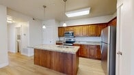 Located at 4151 N Traverse Mountain Blvd in Lehi, Utah, this single-floor, 3-bedroom, 1-bathroom home offers a well-designed layout across a comfortable and functional floor plan. The open-concept kitchen and living area serves as the heart of the home, featuring rich warm-toned wood cabinetry, granite countertops, and a center island with a built-in sink and pendant lighting overhead. Stainless steel appliances, including a range, microwave, and refrigerator, complete the kitchen. Light hardwood-style flooring flows throughout the main living areas, lending a clean and cohesive aesthetic. The living room benefits from generous natural light through large windows and a glass door that opens to the outdoors, offering pleasant neighborhood views. The spacious primary bedroom features plush carpet, dual windows that fill the room with natural light, and ample room to accommodate a full suite of furniture. The two additional bedrooms are similarly carpeted and well-lit with exterior-facing windows. The bathroom includes a full tub-shower combo with clean white finishes and wood-toned vanity cabinetry. A dedicated laundry area with side-by-side full-size washer and dryer adds everyday convenience. A hallway and closet complete the layout, ensuring practical storage throughout.