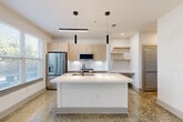 Located at 747 Ralph McGill Blvd NE in Atlanta's vibrant Old Fourth Ward neighborhood, this one-bedroom, one-bathroom residence offers a thoughtfully designed open-concept layout. Light wood-tone flooring runs throughout, complementing the bright white walls and creating a clean, contemporary aesthetic.

The combined kitchen and living area serves as the heart of the home. The kitchen features light natural wood cabinetry, a subway tile backsplash, stainless steel appliances including a French door refrigerator, slide-in range, built-in microwave, and dishwasher. A central island with a white quartz countertop and undermount sink provides both prep space and casual seating. Sleek pendant lighting and a ceiling fan with integrated lighting complete the space. Large windows invite abundant natural light into the kitchen and living area.

The bedroom is a comfortable, well-proportioned retreat outfitted with its own ceiling fan and hardwood-style flooring. Three closets throughout the unit offer generous storage options, supplemented by a dedicated laundry area and utility room.

The bathroom presents a clean, modern design with a wood-vanity base, white quartz countertop, and a tub/shower combination adorned with large-format white tile and matte black fixtures and hardware. A hallway connects all areas of the residence, maintaining a practical and efficient flow throughout.