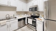 This single-floor residence offers a clean, functional layout with a cohesive neutral color palette and light wood-style flooring throughout. The living and common areas are bright and open, enhanced by recessed lighting and mirrored wall panels that add depth to the space.

The kitchen is well-appointed with white cabinetry, stone-look countertops, and a full suite of stainless steel appliances, including a range, over-the-range microwave, and dishwasher. The layout makes efficient use of space with ample storage and counter workspace.

The bedrooms are comfortably sized, each featuring ceiling fans with light fixtures and windows that bring in natural light with views of surrounding greenery. The primary bedroom includes two mirrored sliding closets, providing generous storage. An additional bedroom offers similar finishes without the closet configuration.

Two bathrooms serve the unit, each featuring shower and tub combinations with curtains and neutral tile surrounds. A dedicated in-unit laundry closet houses a full-size side-by-side washer and dryer with overhead wire shelving for additional storage. Overall, the space presents a practical, move-in-ready environment with consistent finishes throughout.