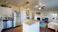Located at 1001 E 1st Ave in Broomfield, Colorado, this single-floor residence offers a thoughtfully designed layout with a seamless flow between its main living areas. The kitchen is outfitted with stainless steel appliances, white cabinetry, a subway tile backsplash, granite countertops, and a center island, all set atop warm hardwood-style flooring. The open-concept design connects the kitchen directly to a bright dining area surrounded by large windows that flood the space with natural light and offer views of the surrounding neighborhood. The living room is anchored by a white-surround fireplace, crown molding, and a ceiling fan, with a built-in study nook providing a dedicated workspace. A glass-paned door in the living area opens to an outdoor space. The bedrooms feature plush carpeting, generous closet space, ceiling fans, and large windows. The bathroom is well-appointed with granite countertops, white cabinetry, a full tub and shower, and hardwood-style flooring. A dedicated in-unit laundry room with side-by-side washer and dryer and overhead shelving adds everyday convenience. Throughout the residence, neutral warm tones and consistent finishes create a cohesive and comfortable living environment.