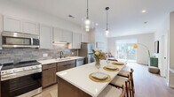 Located at 615 E Corcoran Ave in Milwaukee, Wisconsin, this thoughtfully designed one-bedroom, one-bathroom residence offers a efficient and well-appointed single-floor layout. The open-concept kitchen and living area serves as the heart of the home, featuring two-tone cabinetry with crisp white uppers and warm wood-toned lower cabinets, a grey subway tile backsplash, quartz countertops, and a full suite of stainless steel appliances. A generous kitchen island with bar seating and pendant lighting makes the space ideal for both cooking and entertaining. Light hardwood flooring flows throughout the main living areas, adding warmth and continuity. The living room is bright and inviting, anchored by a sliding glass door that opens to a private balcony, filling the space with natural light and outdoor views. The bedroom is a calm retreat, fitted with plush carpeting, a ceiling fan, and large windows that invite ample daylight. Two closets provide practical storage throughout the unit. The bathroom is finished with matte black fixtures, a wood-toned vanity with a white countertop, and hardwood-style flooring, striking a clean and modern aesthetic. Overall, the space presents a cohesive modern design with high-quality finishes throughout.