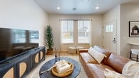 Located at 14712 Mezzaluna Blvd in Oklahoma City, Oklahoma, this single-story, 2-bedroom, 2-bathroom home offers a well-designed open-concept layout with a warm, modern aesthetic throughout. Light wood-tone flooring flows seamlessly across the entire home, complementing the bright white walls and recessed lighting.

The combined kitchen and living area serves as the heart of the home. The kitchen features light wood cabinetry, a white quartz island with bar seating, a subway tile backsplash, and a full suite of stainless steel appliances. An adjacent built-in shelving nook adds practical storage. The living area is spacious and airy, enhanced by vaulted ceilings and a ceiling fan.

Both bedrooms are well-proportioned and filled with natural light from multiple windows, each equipped with ceiling fans. The primary bedroom includes its own closet. The two bathrooms are finished with large-format marble-style tile — one featuring a glass-enclosed walk-in shower, the other a tub-shower combination — both with light wood vanities and wood-tone flooring. A dedicated laundry room with utility connections completes the interior. The property also includes a private outdoor space with artificial turf, visible from the exterior view.