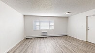 Located at 291 W Belleview Ave in Englewood, Colorado, this two-bedroom, one-bathroom unit offers a practical and well-organized single-floor layout. Consistent light-toned luxury vinyl plank flooring runs throughout, providing a clean, cohesive look across all rooms.

The kitchen is efficiently designed in a galley-style configuration, featuring white cabinetry with brushed nickel hardware, dark countertops, a stainless steel sink, and stainless steel appliances including a refrigerator and dishwasher. A window with blinds brings in natural light, and a baseboard heating unit ensures warmth during colder months.

The adjoining living area is open and versatile, with a wall-mounted air conditioning unit, a baseboard heater, and a wide window fitted with horizontal blinds that allow ample daylight into the space.

Both bedrooms are modest and functional, with neutral white walls, the same LVP flooring, and baseboard heating. Each room offers a quiet, clean environment suited for rest or use as a home office. Two closets serve the unit's storage needs.

The bathroom is well-appointed with white cabinetry, a gray countertop vanity, brushed nickel fixtures, an under-mount sink, and a mirrored medicine cabinet above. The textured ceilings are present throughout the unit, adding a characteristic finish consistent with the building's style.