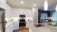 This single-floor residence offers a thoughtfully designed open layout with modern finishes throughout. The kitchen serves as a central highlight, featuring crisp white shaker cabinetry extending to the ceiling, granite countertops, a classic subway tile backsplash, and a full suite of stainless steel appliances including a refrigerator, range, and built-in microwave. A granite-topped center island with bar seating and pendant lighting above provides additional prep space and a casual dining option. Adjacent to the kitchen, a dedicated dining area accommodates a small table, while wood-style flooring flows seamlessly throughout the main living areas, enhancing the cohesive aesthetic.

The bedrooms are comfortably sized, each featuring large windows that invite natural light, ceiling fans, and neutral tones that contribute to a calm atmosphere. The primary bathroom is well-appointed with a granite vanity, wood-style flooring, a walk-in shower with tile surround, and direct access to a spacious walk-in closet with built-in shelving. Recessed lighting and clean white walls throughout the residence create a bright, modern ambiance.