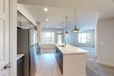 Located at 180 Jackson St NE in Atlanta's vibrant Old Fourth Ward neighborhood, this one-bedroom, one-bathroom residence offers a thoughtfully designed single-floor layout with modern finishes throughout. The open-concept kitchen serves as the heart of the home, showcasing slate-gray cabinetry, a subway tile backsplash, stainless steel appliances including a refrigerator, range, and microwave, and a generous island with a quartz countertop and undermount sink. Stylish pendant lighting with a brushed brass finish adds character to the space. The kitchen flows seamlessly into the living area, which features plush carpeting, a ceiling fan, and multiple windows that invite an abundance of natural light. A private balcony provides an outdoor retreat accessible from the living area. The bedroom is a well-proportioned, carpeted retreat with a ceiling fan and a window offering natural light. The bathroom is finished with a gray vanity, quartz countertop, glass-enclosed shower, and wood-look flooring. A dedicated walk-in closet connects directly to the bathroom, offering convenient and organized storage. Recessed lighting throughout completes the clean, contemporary aesthetic of this well-appointed Atlanta residence.