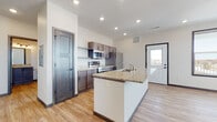 This single-floor residence offers a thoughtfully designed layout that balances functionality and modern style throughout. The heart of the home is an open-concept kitchen and living area, where light wood-look flooring flows seamlessly underfoot. The kitchen is anchored by a generous island topped with granite countertops and an integrated sink, providing ample workspace and a natural gathering point. Dark-stained cabinetry lines the kitchen walls, complemented by a full suite of stainless steel appliances including a refrigerator, range, and over-the-range microwave. Recessed lighting illuminates the space, while large windows in the living area flood the room with natural light and offer views of the surrounding neighborhood. A ceiling fan adds both style and practicality to the living space.

The bedrooms are carpeted for comfort, each featuring sizable windows that bring in natural light and views of the outdoors. Dark-trimmed doors and dark baseboards provide a consistent design contrast against the neutral walls throughout the unit.

The bathrooms continue the home's cohesive aesthetic, featuring granite-topped vanities with dark cabinetry, framed mirrors, and stylish vanity lighting. One bathroom includes a walk-in shower stall with wood-look flooring, maintaining the clean, modern feel found throughout this well-finished residence.