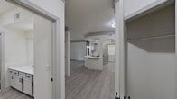 This contemporary single-floor residence boasts a spacious and airy design. The interior showcases light wood flooring throughout, complemented by crisp white walls that enhance the sense of openness. Multiple rooms feature modern ceiling fans and large windows, allowing for natural light and views of the surrounding landscape. The home includes a dedicated laundry area with side-by-side appliances, and a renovated bathroom with a tub-shower combination and stylish vanity lighting. A standout feature is the sliding glass door leading to an outdoor area, seamlessly connecting indoor and outdoor living spaces. Ample storage solutions are integrated throughout, including built-in closet systems, ensuring a clutter-free environment.