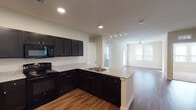 This single-story residence is thoughtfully designed with an open-concept layout that seamlessly connects the kitchen and living areas. The kitchen is a standout feature, showcasing dark espresso cabinetry that extends to the ceiling, light granite countertops, and a peninsula with an integrated sink — providing both additional workspace and a natural divide between the kitchen and the living space. Black appliances, including a refrigerator, range, microwave, and dishwasher, complement the cabinetry. Recessed lighting and track lighting illuminate the space effectively.

Wood-style flooring flows throughout the main living areas and bedrooms, contributing to a cohesive aesthetic. The living area is bright and open, benefiting from natural light through large windows and a ceiling fan overhead. Bedrooms offer plush carpeting, ample natural light, and generous closet space — including a spacious walk-in closet with built-in wire shelving.

The bathrooms are well-appointed with dark vanity cabinetry, white countertops, and tub-shower combinations. The primary bath features direct access to the walk-in closet. Neutral wall tones throughout create a clean, move-in-ready canvas.