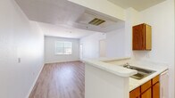 Located at 15255 E 40th Ave in Denver, Colorado, this 2-bedroom, 1-bathroom residence offers a practical and well-organized single-floor layout. Light wood-style flooring runs throughout the home, creating a clean, cohesive aesthetic. The open-concept living and kitchen area forms the heart of the home, with the kitchen featuring warm wood cabinetry, a light-toned countertop peninsula with a sink, white appliances including a refrigerator and dishwasher, and ample cabinet storage on both sides of the galley-style workspace. The adjacent living room is bright and airy, bathed in natural light from a large window with views of the surrounding neighborhood. Both bedrooms are well-proportioned, each offering light-filled windows with blinds and light wood flooring. The primary bedroom includes a closet with double panel doors. The full bathroom is thoughtfully equipped with a tub-shower combination featuring white tile surround, grab bars for added accessibility, a wood-toned vanity with a white countertop and sink, and matching wood flooring. The home maintains a bright, neutral palette throughout, with white walls and clean finishes that provide a versatile and welcoming living environment.