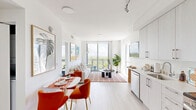 Located in Miami, FL, this thoughtfully designed one-bedroom, one-bathroom residence offers a bright and efficient layout finished in a clean, contemporary style. Light wood-tone flooring runs throughout, complementing the all-white palette that amplifies the abundant natural light pouring in through floor-to-ceiling windows and sliding glass doors.

The open-plan living and dining area is the heart of the unit, where expansive glazing frames sweeping views of Miami's treetop skyline. A sliding glass door opens directly onto a private balcony, extending the living space outdoors. The kitchen sits adjacent to the dining area and features white flat-front cabinetry extending to the ceiling, stainless steel appliances including a French-door refrigerator, range, and built-in microwave, plus a clean white countertop with an undermount sink.

The bedroom is a serene retreat, with a large picture window framing broad outdoor views and ample space for a full sleeping suite. A dedicated closet and hallway provide practical storage and circulation. The bathroom is finished with a white vanity and clean, simple fixtures. Track lighting in the kitchen and recessed lighting throughout ensure versatile illumination across every room, making this a well-appointed urban residence.