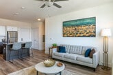 Located at 55 Park Ave in Bay Shore, NY, this single-floor residence offers a thoughtfully designed open-concept layout finished with light hardwood flooring throughout. The kitchen serves as a central hub of the living space, featuring two-tone cabinetry with white upper cabinets and dark lower units, a subway tile backsplash, stainless steel appliances including a refrigerator, range, microwave, and dishwasher, and a dark-topped island with seating. Track lighting overhead provides functional illumination across the cooking and dining area.

The adjoining living area benefits from multiple windows that invite generous natural light and offer outdoor views. A ceiling fan adds comfort, while the open flow between kitchen and living space creates a cohesive, airy atmosphere suited for daily living and entertaining.

Two bedrooms are each appointed with hardwood flooring, large windows with natural light and exterior views, and wall-unit climate control. The bedroom layouts offer comfortable proportions and a calm, neutral aesthetic.

The bathroom is finished with large-format tile flooring, a glass-enclosed walk-in shower with white subway tile and a contrasting mosaic accent strip, and a dark wood vanity topped with a white countertop and framed mirror with contemporary lighting above.