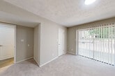 Located at 3859 Flat Shoals Pkwy in Decatur, GA, this 2-bedroom, 1-bathroom residence offers a practical and well-appointed single-floor layout. The living room features durable wood-look flooring, neutral gray walls, a textured ceiling, and a built-in open shelving unit, with a front entry door providing a clean, welcoming feel. A sliding glass door in the adjacent area fills the space with natural light and offers views of the surrounding greenery.

The galley-style kitchen is a standout feature, showcasing white shaker cabinets, granite-style countertops, a classic subway tile backsplash, a stainless steel sink with a modern faucet, and black appliances including a refrigerator, range, and dishwasher. Wood-look flooring continues throughout the kitchen and hallway.

Both bedrooms are carpeted for comfort. The primary bedroom is generously sized, featuring two windows that bring in natural light and views of the tree-lined exterior. The second bedroom offers a sliding glass door for additional outdoor light and access. A hallway connects the rooms to the shared bathroom, which includes a granite-topped vanity, white cabinetry, a large mirror, and a tub-shower combination with wood-look flooring.