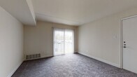 This single-floor residence offers a functional and comfortable layout designed to maximize livability. The living area is finished with plush wall-to-wall carpeting and features a large sliding glass door fitted with vertical blinds, allowing generous natural light to fill the space while providing access to an outdoor area. Neutral warm-toned walls and clean white trim throughout create a bright, cohesive aesthetic.

The kitchen is well-equipped and practical, featuring warm wood cabinetry with ample upper and lower storage, granite-look countertops, and stone-tile flooring. White appliances include a gas range, over-the-range microwave, dishwasher, and a full-size refrigerator, making the space move-in ready.

The bedrooms are generously proportioned, each carpeted and filled with natural light from multiple windows. One bedroom stands out with dual closets offering abundant storage. An additional room provides a flexible, open space suitable for a variety of uses.

The bathroom is finished with light tile flooring, a wide vanity with under-sink storage, a large mirror, and elegant brushed nickel fixtures. A ceiling fan in the central area of the home adds to the overall comfort and ventilation of the space. The layout is thoughtfully designed for ease of living throughout.