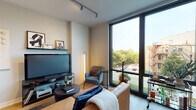 Located at 723 N Ogden Ave in Chicago's vibrant West Town neighborhood, this contemporary single-floor residence showcases thoughtful design and high-end finishes. The living area is anchored by dramatic floor-to-ceiling windows that flood the space with natural light and offer open views of the surrounding streetscape and tree-lined neighborhood. Track lighting and warm wood flooring complement the modern aesthetic, while a dedicated dining nook with a compact table adds everyday functionality.

The kitchen is a standout feature, outfitted with slate-blue flat-front cabinetry, white quartz countertops, a marble-style tile backsplash, and a full suite of stainless steel appliances, including a gas range and over-the-range microwave. The space is both stylish and highly functional.

The bedroom provides a calm retreat, with access to a well-organized walk-in closet and continued views to the outdoors through large windows that connect the room to the living area's bright atmosphere.

The bathroom is finished with large-format marble-look tile flooring, a clean white vanity with a warm wood cabinet base, and a full mirror — delivering a polished, spa-like feel. Throughout the unit, clean lines, neutral tones, and contemporary fixtures create a cohesive and refined living environment.