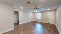 This single-floor home presents a well-maintained, move-in-ready interior with a consistent and cohesive design throughout. Rich wood-look vinyl plank flooring extends across all rooms, providing a warm and durable foundation that ties the space together seamlessly.

The open living areas are generously proportioned, with neutral beige walls, crisp white baseboards, and ceiling fans fitted with integrated lighting in each room. Recessed lighting in select areas adds a modern touch and enhances overall brightness. Windows dressed with white horizontal blinds allow natural light to filter in while offering privacy.

The kitchen is outfitted with white upper cabinetry featuring crown molding detail, stainless steel appliances including a full-size refrigerator and range, and direct access to an exterior door — a practical and functional layout.

Multiple bedrooms offer comfortable living spaces, each equipped with a ceiling fan and windows that bring in natural light. The rooms maintain the same neutral palette, offering a clean and versatile canvas.

The bathroom features a full tub-shower combination with classic white subway tile surround, brushed gold fixtures, and wood-look flooring that continues from the main living areas, contributing to the home's unified aesthetic.

Overall, this home delivers a clean, functional, and well-appointed living environment with thoughtful finishes throughout.