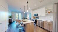 Located on Payne Street in Dover, NH, this modern 2-bedroom, 3-bathroom residence offers a thoughtfully designed single-floor layout with clean contemporary finishes throughout. The open-concept kitchen and living area serves as the heart of the home, where the kitchen stands out with its two-tone cabinetry — white upper cabinets paired with warm natural wood lowers — complemented by white quartz countertops, a subway tile backsplash, and a full suite of stainless steel appliances. A central island with pendant lighting provides additional prep space and casual seating. The adjoining living room is bright and welcoming, with hardwood-style flooring and a glass door leading to an outdoor balcony with open views. The primary bedroom is generously sized, featuring carpet flooring, large windows with outdoor views, and access to its own well-appointed bathroom. A second bedroom offers a comfortable retreat with soft carpet and clean white walls. Both secondary bathrooms feature warm wood vanities, white quartz counters, large mirrors, and hardwood-style flooring. Two dedicated closets, including a spacious walk-in with built-in shelving, provide ample storage. The overall aesthetic is modern, light-filled, and move-in ready.