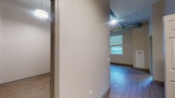 Located at 64 E Cermak Road in Chicago's Near South Side, this single-floor unit blends modern finishes with industrial architectural character. Exposed ductwork runs along the elevated ceilings, lending an urban loft aesthetic to the open living and kitchen area. Light wood-tone flooring extends throughout, creating a cohesive and clean look across all spaces.

The kitchen is well-appointed with stainless steel appliances, including a full-size refrigerator, dishwasher, and over-the-range microwave. White flat-front cabinetry reaches toward the ceiling, maximizing storage, while a continuous countertop provides ample prep space. Natural light filters in through windows fitted with roller shades, brightening the main living area.

The bedroom features a dedicated closet with a rod-and-shelf system and direct access to a bathroom, providing a convenient layout. A second bathroom is also present, one offering a walk-in shower with grab bars and a floating vanity, and the other a tub-shower combination with a mirrored medicine cabinet. Both bathrooms are finished in neutral tones with wood-look flooring. The overall design is clean, functional, and well-suited for urban living.