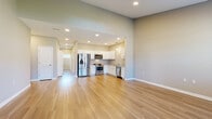 Located at 4866 Fulton Dr NW in Canton, Ohio, this single-floor home offers a thoughtfully designed open-concept layout that seamlessly connects the living and kitchen areas. The kitchen is a standout feature, outfitted with crisp white shaker cabinetry, granite-style countertops, and a full suite of stainless steel appliances including a French door refrigerator, range, microwave, and dishwasher. Light hardwood-style flooring runs throughout the main living spaces, enhancing the bright and airy atmosphere. The living area benefits from a dramatic skylight and large windows that flood the space with natural light, while a front entry door with sidelights provides a welcoming entrance. Bedrooms feature plush carpeting and ceiling fans, with sliding glass doors in at least one room that open to outdoor views. The bathroom is finished with white cabinetry, granite countertops, wood-look tile flooring, and above-toilet storage. A dedicated laundry closet houses a full-size Maytag washer and dryer. Neutral warm-gray tones throughout the home create a cohesive, modern aesthetic that complements the clean architectural lines and recessed lighting found in every room.