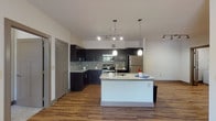 This single-floor, 2-bedroom, 2-bathroom residence offers a thoughtfully designed layout with modern finishes throughout. The open-concept kitchen serves as a central highlight, featuring dark cabinetry, a mosaic tile backsplash, stainless steel appliances including a refrigerator, range, and built-in microwave, and a large island with a granite countertop and undermount sink. Pendant and track lighting illuminate the space, while warm wood-style flooring extends seamlessly into the living areas, creating a cohesive and inviting atmosphere.

The bedrooms are generously sized, each equipped with ceiling fans and ample natural light. One bedroom offers a sliding glass door leading to an outdoor balcony, while the second features a pair of windows with views of surrounding greenery. The bedrooms are finished with plush carpeting for added comfort.

Both bathrooms are outfitted with dark wood vanities, granite countertops, and wood-style flooring that mirrors the rest of the home. A dedicated utility and storage room provides built-in shelving and additional organizational space. The overall design balances contemporary style with functional living, making this a practical and attractive residence.