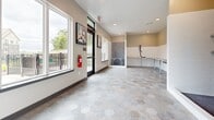 Located on Needham Drive in Smyrna, Tennessee, this single-floor pet spa is a purpose-built facility designed to accommodate pet grooming and bathing needs. The space is thoughtfully laid out within a compact but efficiently organized footprint, maximizing functionality throughout.

The interior features distinctive large-format hexagonal tile flooring in neutral gray tones, providing a durable and easy-to-clean surface suited to its function. A dedicated dog wash station occupies one end of the room, enclosed by white subway tile walls and equipped with a handheld showerhead and a raised washing platform. Adjacent to the wash area, a built-in grooming counter runs along the wall, outfitted with wall-mounted pet dryers on adjustable arms.

Recessed ceiling lighting illuminates the space evenly, complemented by abundant natural light streaming through multiple windows along the exterior walls. The windows offer views of the surrounding outdoor areas and landscaping. A glass-panel entry door enhances the openness of the space.

Wall-mounted pet-themed artwork adds a welcoming touch, while neutral warm-toned walls contribute to a clean, professional ambiance. A floor drain and safety equipment, including a fire extinguisher, reflect the practical design considerations built into this well-appointed pet care space.