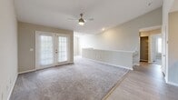 Located in the Colonial Village community of Tampa, FL, this two-story home offers three bedrooms, two full bathrooms, and a thoughtfully designed layout spread across two floors. The main living level is anchored by a modern kitchen featuring white shaker-style cabinetry with black hardware, a subway tile backsplash, stainless steel appliances, and a peninsula with a light stone countertop and undermount sink — ideal for both cooking and casual dining. Light wood-look tile flooring runs throughout the kitchen and adjoining dining area, adding warmth and easy maintenance. The open living area is carpeted and filled with natural light from French doors that lead outside, complemented by a ceiling fan overhead. Each of the three bedrooms is carpeted and equipped with a ceiling fan. The spacious primary bedroom includes a generous walk-in closet with built-in wire shelving. Additional bedrooms feature large windows that invite natural light. Both bathrooms are finished with wood-look tile flooring, white vanities with black hardware, and tub-shower combinations with clean white tile surrounds. A dedicated laundry area and two closets add practical storage. A staircase connects the entry-level foyer to the main living floor above.