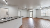 This single-story home at 15330 Liberty River Dr in Houston, Texas offers a thoughtfully designed layout with a clean, neutral aesthetic throughout. The open-concept living and dining area is anchored by rich hardwood-style flooring, a ceiling fan, and natural light from front-facing windows. Track lighting adds a modern touch to the space, which also features built-in shelving — ideal for display or storage.

The kitchen is well-appointed with dark espresso cabinetry, granite-style countertops, black appliances including a range, built-in microwave, and dishwasher, along with a double sink. A peninsula counter separates the kitchen from the main living area, creating an open yet defined flow.

The bedrooms feature plush carpeting and ceiling fans, with one offering direct access to a bathroom and a generous walk-in closet outfitted with wire shelving. The bathroom includes a wide vanity with dark wood cabinetry, a stone-tone countertop, and a large mirror with overhead lighting.

Additional highlights include a dedicated in-unit laundry area, ample closet storage, and an entry door with transom window that brings in added natural light. The home presents a practical and comfortable living environment in a well-connected Houston location.