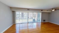 Located at 3505 Chamberlayne Ave in Richmond, Virginia, this single-floor unit offers a straightforward and functional layout with consistent finishes throughout. The living area is a standout feature, showcasing polished hardwood floors that reflect natural light pouring in through expansive sliding glass doors dressed with vertical blinds. These doors open to an outdoor area, seamlessly connecting interior and exterior living. A ceiling fan overhead adds to the comfort of this bright, open space.

The bedrooms continue the warm hardwood flooring and are finished with neutral gray walls and clean white trim, creating a calm and versatile backdrop. One bedroom benefits from a well-sized window with blinds, while another features a built-in closet with sliding doors for convenient storage.

The kitchen is compact and efficiently arranged, with dark espresso cabinetry providing ample storage above and below a light countertop with a double-basin stainless steel sink. Tile flooring in this area offers a practical contrast to the hardwood found elsewhere in the unit.

The bathroom retains a retro character, highlighted by light blue ceramic tile surrounding a full bathtub and shower combination, paired with classic chrome fixtures. Throughout the space, neutral tones, hardwood floors, and abundant natural light create a clean and livable environment.