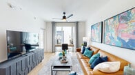 Located at 805 N Olive Ave in West Palm Beach, FL, this thoughtfully designed 2-bedroom, 1-bathroom residence delivers a modern living experience with a clean, contemporary aesthetic throughout. The open-concept layout seamlessly connects the kitchen, dining, and living areas, creating a cohesive and functional flow. The kitchen is a standout feature, outfitted with two-tone navy and white cabinetry, stainless steel appliances including a French door refrigerator, a sleek subway tile backsplash, and a central island with bar seating and pendant lighting overhead. Light wood-style flooring runs throughout, enhancing the bright and airy ambiance. The living room is generously proportioned, filled with natural light from large windows and a sliding glass door, and is accented by a modern ceiling fan. The primary bedroom offers a comfortable retreat with multiple windows, a ceiling fan, and a walk-in closet accessed through charming barn-style doors. The bathroom features white cabinetry, black hardware accents, and clean tile flooring. A stylishly appointed accent wall with floating shelves and an arched mirror adds a designer touch near the dining area, rounding out this well-appointed West Palm Beach residence.