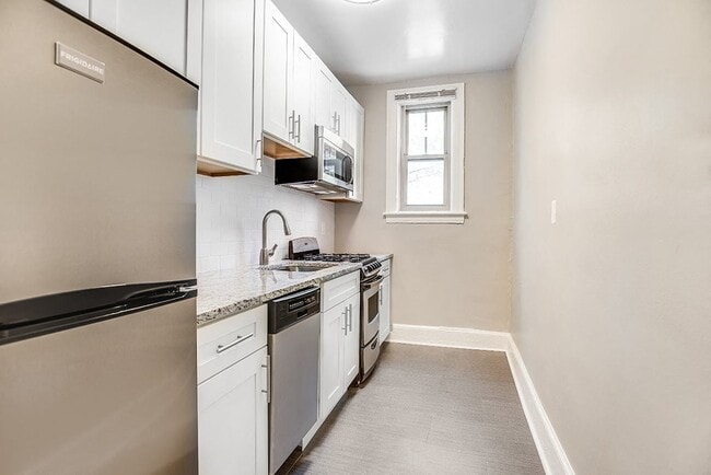 Renovated kitchen with granite countertops and stainless steel appliances - President Madison Apartments