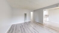 Located at 211 S Western Ave in Anaheim, CA, this single-floor, 2-bedroom, 1-bathroom unit offers a clean and modern living environment with a cohesive neutral palette throughout. Light gray walls pair seamlessly with light-toned luxury vinyl plank flooring found in every room, creating a bright and airy atmosphere.

The open living area is well-lit by a large window with vertical blinds that invites natural light, and features a wall-mounted A/C unit and a vertical floor-to-ceiling heating unit. The space connects directly to the kitchen, which is outfitted with white shaker-style cabinetry, recessed lighting, a stone tile backsplash, and a gas range — a practical and stylish setup for everyday cooking.

The two bedrooms are comfortably sized, with the primary bedroom offering dedicated closet space and a wall vent. Both rooms feature the same light flooring and neutral gray walls, maintaining a calm and consistent feel. A hallway connects the bedrooms to the shared full bathroom, which stands out with a long dual-sink vanity topped with a white marble-style quartz countertop, a full-width mirror, globe vanity lighting, and a medicine cabinet.

Textured ceilings are consistent throughout the unit. The overall design is clean, functional, and move-in ready.