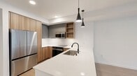 This contemporary 810 square foot apartment in Redmond, WA offers a blend of modern design and functionality. The space features two bedrooms, including a primary bedroom of 160 square feet, and one bathroom. The open-concept layout seamlessly integrates the kitchen and living areas, creating a spacious feel within the compact footprint.

The kitchen is a highlight, boasting sleek wooden cabinetry contrasted with stainless steel appliances, including a side-by-side refrigerator and built-in microwave. A white quartz countertop with an undermount sink adds a touch of elegance, while pendant lighting provides both style and illumination.

Throughout the apartment, light-toned wood flooring enhances the bright and airy atmosphere. Large windows in the bedrooms and living area flood the space with natural light and offer views of the surrounding area. The bathroom features clean white tiles and modern fixtures, with a convenient adjacent laundry area.

Storage solutions are thoughtfully integrated, including a walk-in closet and built-in shelving. The private balcony extends the living space outdoors, perfect for enjoying fresh air or urban views. With its contemporary design and efficient use of space, this apartment offers comfortable city living in a prime Redmond location.