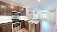 This well-appointed 2-bedroom, 2-bathroom residence at 8 Kingsbridge Road in Fairfield, NJ offers a modern, open-concept layout designed for comfortable everyday living. The kitchen serves as the heart of the home, featuring rich dark-brown cabinetry extending to the ceiling, a white subway tile backsplash, quartz countertops, and a full suite of stainless steel appliances including a gas range, built-in microwave, dishwasher, and refrigerator. A peninsula with seating potential connects the kitchen seamlessly to the living area, which is accented by a distinctive sliding barn door and a ceiling fan, adding both character and functionality. Light wood-look flooring flows throughout the main living areas, creating a warm and cohesive aesthetic. The bedrooms are carpeted for comfort, with large windows that invite natural light and offer views of the surrounding neighborhood. The bathrooms are finished with clean, contemporary fixtures, including a rectangular undermount sink set in a crisp white vanity top. A dedicated closet and thoughtful hallway layout provide practical storage solutions. Recessed lighting throughout enhances the bright, airy ambiance of this move-in-ready Fairfield residence.
