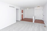 Located on Shiawassee Road in Southfield, Michigan, this single-floor unit offers a practical and comfortable layout with a clean, neutral aesthetic throughout. The living area is generously proportioned, featuring plush wall-to-wall carpeting, crisp white walls, and a large window dressed with vertical blinds that allows natural light to fill the room. A wall-mounted air conditioning unit provides direct climate control in this space.

The galley-style kitchen is efficiently arranged with warm wood-toned cabinetry lining both sides, complemented by granite-look countertops, a double sink, and white appliances including a range and refrigerator. Hardwood-style flooring runs through the kitchen, adding warmth and easy maintenance underfoot.

The bedrooms are carpeted and bright, each equipped with a ceiling fan and light fixture. Closet space is well incorporated, with open shelving visible through paneled closet doors. The transition area between rooms features a mix of hardwood-style and carpeted flooring, creating clear distinctions between living zones.

The bathroom is cleanly finished with a dual-sink vanity topped with a stone-look countertop, white cabinetry with brushed nickel hardware, a lighted mirror, and a full soaking tub with a tiled surround, all set on hardwood-style flooring for a cohesive and polished look.