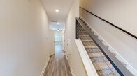 Located at 957 Woody Dr in Graham, NC, this well-appointed two-story home showcases modern finishes and a thoughtfully designed layout across both levels. The kitchen serves as a central highlight, featuring crisp white cabinetry with matte black hardware, granite countertops, a large island with an undermount sink, stainless steel appliances including a refrigerator, microwave, and range, and pendant lighting that adds a contemporary touch. The adjacent living area is bright and open, with luxury vinyl plank flooring, recessed lighting, a ceiling fan, and French doors that invite natural light and outdoor access. A staircase with sleek cable railings and carpeted treads connects the two floors, leading to a hallway that flows to the upper-level rooms. Bedrooms are carpeted for comfort and include spacious closets outfitted with wire shelving systems. Bathrooms are finished with granite-topped vanities, matte black fixtures, and tiled tub-shower combinations. Neutral warm-toned walls and white trim are consistent throughout, creating a clean, cohesive aesthetic. The home offers a balance of functional design and modern style, making it a well-equipped residence in Graham, North Carolina.