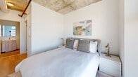 Located on the 16th floor at 748 Bathurst Street in Toronto's vibrant Annex neighbourhood, this three-bedroom, two-bathroom unit offers a compelling industrial-modern aesthetic across a compact, efficiently laid out single floor. Exposed concrete ceilings and structural columns are defining architectural features throughout, contrasting cleanly against bright white walls and light-toned hardwood flooring to create a contemporary urban character.

The primary bedroom benefits from a large window framing panoramic views of the Toronto skyline, filling the room with natural light. A second bedroom similarly enjoys elevated city and neighbourhood views through a generous window, while the third bedroom, well-suited as a nursery or flex room, features the same exposed concrete ceiling and warm wood floors.

The two bathrooms are finished with large-format neutral tiles. One includes a soaking tub with white tile surround and a light wood vanity, while the second bathroom maintains the same clean, minimal palette with a wood-toned vanity and ample counter space. A dedicated closet and hallway provide practical storage and circulation throughout the unit. The overall ambiance is bright, calm, and modern, with the raw concrete elements lending an industrial edge to an otherwise serene interior.