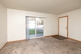 Located at 3855 Pine View Place in Waterloo, Iowa, this single-floor, three-bedroom, one-bathroom home offers a practical and well-organized layout. The living room features soft carpeting and opens into an adjacent dining area, creating a connected common living space. A ceiling fan with light fixture and wood-look vinyl flooring distinguish the entry area, which also houses an electrical panel and a louvered interior door, adding a warm, functional touch. The kitchen is well-equipped with abundant honey-toned oak cabinetry, granite-patterned countertops, a coil-element range, refrigerator, and a sink — all complemented by wood-look flooring that ties the space together. The three bedrooms are carpeted and finished with clean white walls and warm wood baseboards; one bedroom includes a closet with a louvered door and a window providing natural light. The full bathroom features a tub-shower combo with a handheld showerhead, grab bars for accessibility, and wood-look flooring. Two hallways connect the rooms efficiently throughout the home. The overall aesthetic is clean and neutral, offering a move-in ready canvas with consistent warm wood accents throughout.