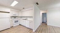 Located at 825 Cypress St in Tarpon Springs, Florida, this single-floor, 2-bedroom, 1-bathroom home offers a bright and functional layout with a clean, modern aesthetic throughout. Light-toned luxury vinyl plank flooring runs consistently through the main living areas and bedrooms, tying the space together with a cohesive, contemporary look.

The open kitchen is well-appointed with white flat-panel cabinetry, a tile mosaic backsplash, white appliances including a range, built-in microwave, and dishwasher, and a stainless steel sink. It flows directly into the combined dining and living area, which features a textured ceiling, a decorative chandelier, and a window that brings in natural light.

The two bedrooms are comfortably sized, each with closet storage and windows offering outdoor views of surrounding greenery. The primary bedroom includes a large bi-fold closet. The shared bathroom is finished with neutral tile, a tub-shower combination, and a vanity with a light countertop.

A dedicated laundry area with a stacked washer and dryer adds significant convenience. A hallway connects the rooms efficiently, and three closets throughout the home provide ample storage. The overall ambiance is clean, minimal, and move-in ready.